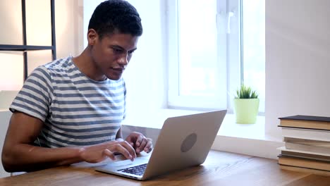 Schwarzer-Mann-feiert-Erfolg-während-der-Arbeit-am-Laptop