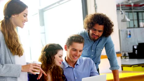 Business-executives-discussing-over-laptop-in-meeting