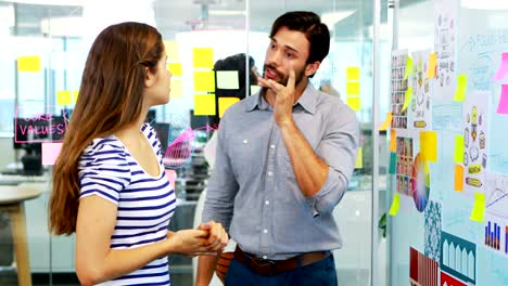 Male-and-female-executive-discussing-over-whiteboard