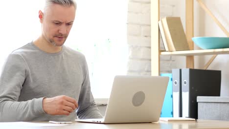 Mann-mittleren-Alters-kommen-zur-Arbeit,-beginnt-auf-Laptop