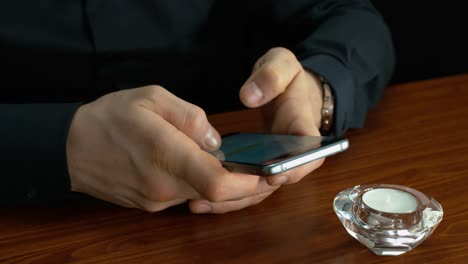 Businessman-Using-A-Mobile-On-A-Brown-Desk-By-A-Candle