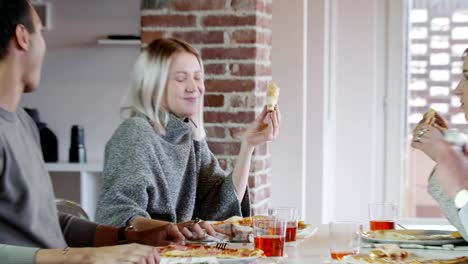 multiethnic-group-of-friends-people-enjoy-having-lunch-or-dinner-meal-together-eating-pizza-indoor-in-modern-industrial-house.-4k-handheld-video-shot