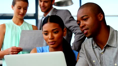 Business-executives-discussing-over-laptop