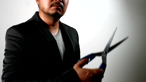 Businessman-in-Black-Suit-showing-scissor-in-aggressive-emotion-on-white-wall-background.