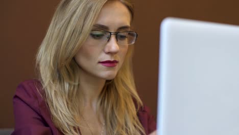 Junge-attraktive-Geschäftsfrau-arbeiten-an-modernen-Laptop-im-café