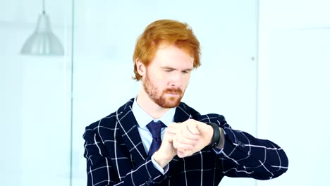 Redhead-Businessman-Using-Smartwatch-at-Work-in-Office