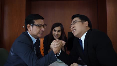 Business-people-arm-wrestling-at-desk-in-the-office