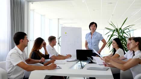 Gruppe-von-Menschen-ins-Büro-Kleidung-am-Schreibtisch-und-Mentor-in-der-Nähe-von-Whiteboard-im-Businesscenter