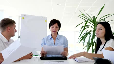 Business-meeting-of-collaborators-at-desk-with-documents-in-hand-in-boardroom