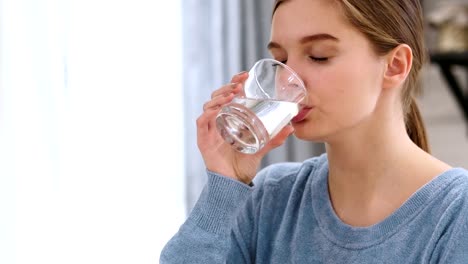 Hermosa-mujer-bebiendo-agua-de-vidrio-en-casa