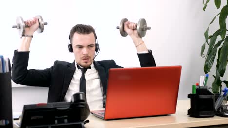 Young-man-in-a-suit-is-working-in-the-office-and-doing-an-exercise-for-the-shoulders-with-a-dumbbell-60-fps