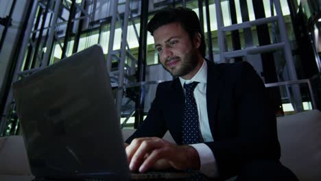 Arabic-male-business-traveller-laptop-night-hotel-atrium