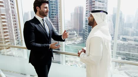 Middle-Eastern-and-Caucasian-businessmen-meeting-downtown-building