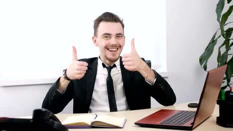 Young-businessman-in-suit-sitting-in-office-and-showing-thumbs-up-sign-60-fps