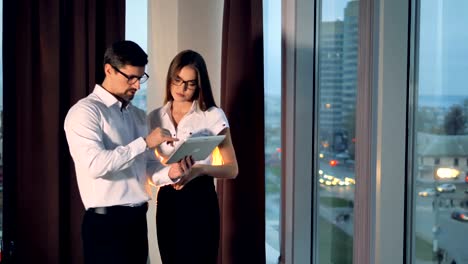 A-businessman-shows-his-project-on-a-tablet-to-a-woman.