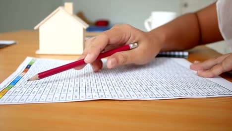 4K-Close-up-shot-hands-of-woman-reading-to-number-in-the-paper-on-table