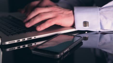 Caucasian-Men-Working-in-His-Office-Let-Hours.-Smartphone-and-Laptop-Devices-in-Use.