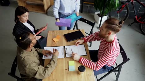 Top-view-of-young-asian-woman-sharing-architectural-plans-with-multi-ethnic-team-and-discussing-new-start-up-project-in-modern-office