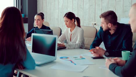 Frau-im-Gespräch-mit-Kollegen-bei-einem-Treffen,-sitzen-an-einem-Tisch-im-Büro