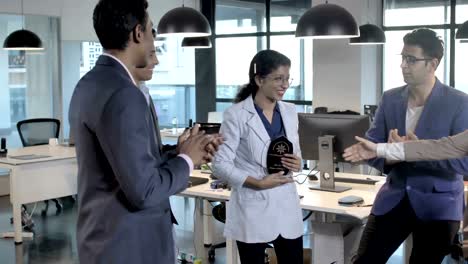 Group-of-male-and-female-coworkers-clapping-and-celebrating-a-success-of-a-lady-colleague