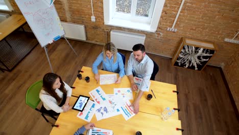 Reunión-de-negocios-en-el-loft-espacio-compartido.-Equipo-hablando,-mujer-Gerente-dando-sentido-a-las-personas.-Vista-superior.