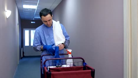 Male-hotel-cleaner-putting-on-gloves-before-cleaning-the-room