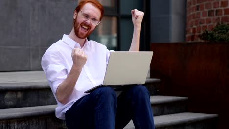 Aufgeregt-Mann-feiert-Erfolg-auf-Laptop-sitzend-auf-Büro-Treppen