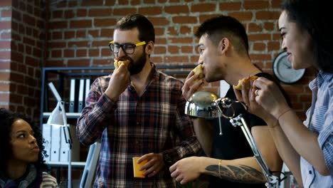 Kolleginnen-und-Kollegen-im-Büro-zusammen-Pizza-Essen