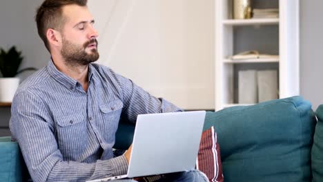 Nachdenklicher-Mann-arbeitet-am-Laptop-im-Schlafzimmer