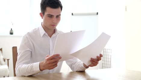 Businessman-Reading-Contract-Papers-in-Office