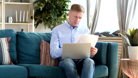 Middle-Aged-Man-Working-on-Documents-and-Laptop