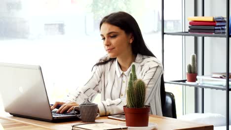 Attractive-young-businesswoman-enjoying-working-at-her-office