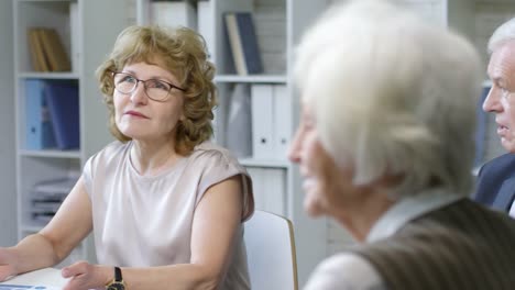 Senior-geschäftsfrau-am-Meeting-sprechen