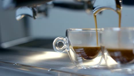 Super-Slow-Motion-von-heißen-Espresso-Kaffee-Gießen-in-ein-zwei-weiße-Porzellantassen-aus-Kaffeemaschine-in-4k-(Draufsicht-Nahaufnahme)