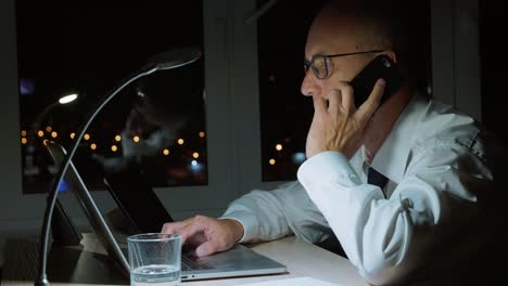 Executive-businessman-chatting-to-mobile-phone-while-last-work-in-business-office