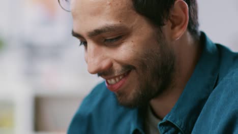 Close-up-Elevating-Shot-of-Handsome-Man-Typing-on-a-Laptop-and-Smiling.