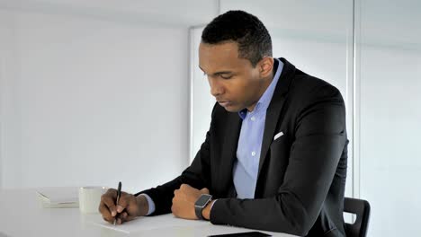 Casual-Afro-American-Businessman-Writing-at-Work,-Paperwork