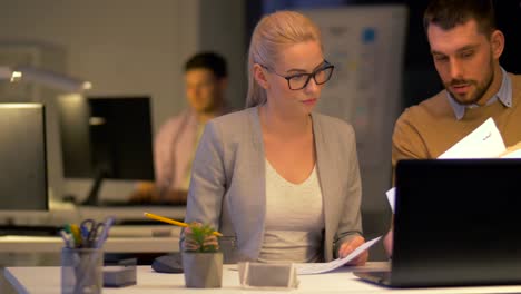 equipo-de-negocios-con-ordenador-portátil-a-trabajar-en-oficina-de-noche