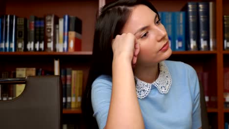 portrait-of-pretty-tired-business-woman-having-headache-sitting-at-office-desk-bookshelf-background