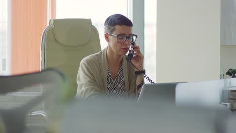 Mujer-de-negocios-hablando-por-teléfono-y-el-uso-del-ordenador-portátil