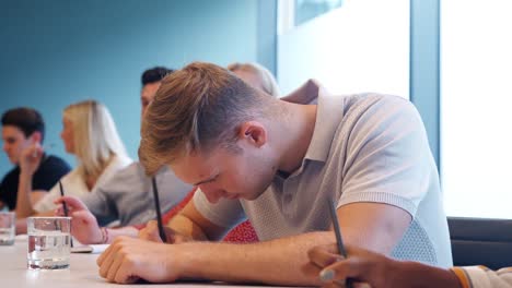 Gruppe-der-jungen-Kandidaten-sitzen-am-Konferenztisch-Notizen-am-Werktag-Graduate-Recruitment-Bewertung