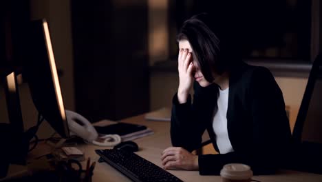 Tired-young-lady-is-working-late-hours-in-office-using-computer-then-rubbing-her-temples-trying-to-reduce-headache-and-fatigue.-Technology-and-overwork-concept.