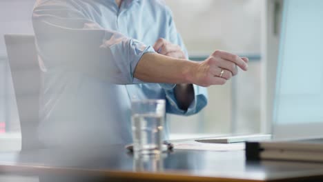 business-man-at-office-desk-rolling-up-right-sleeve