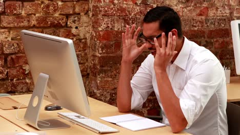 Casual-businessman-getting-stressed-out-at-his-desk