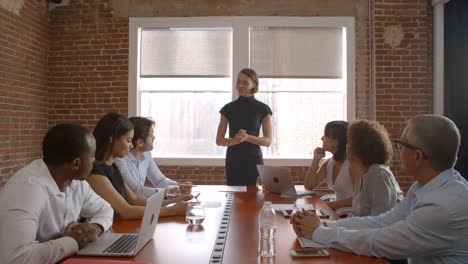 Empresaria-de-pie-para-abordar-reunión-de-sala-de-juntas