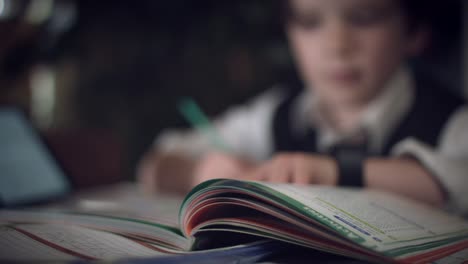 4K-Hi-Tech-Shot-of-a-Child-Doing-Homework,-focus-changing-to-book