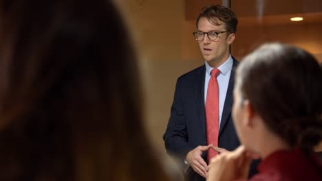 Over-shoulder-view-of-young-businessman-talking-at-a-meeting