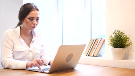 Pensive-Young-Girl-Working-on-Laptop-in-Office