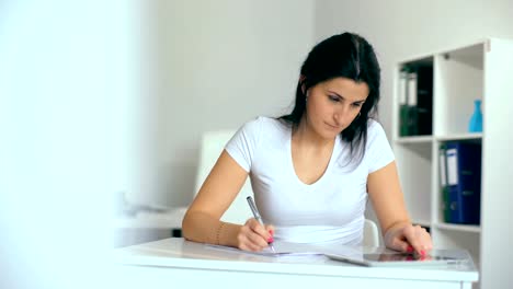 Beautiful-young-woman-writing-something-in-her-notepad