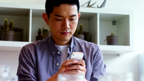 Man-using-mobile-phone-at-his-desk